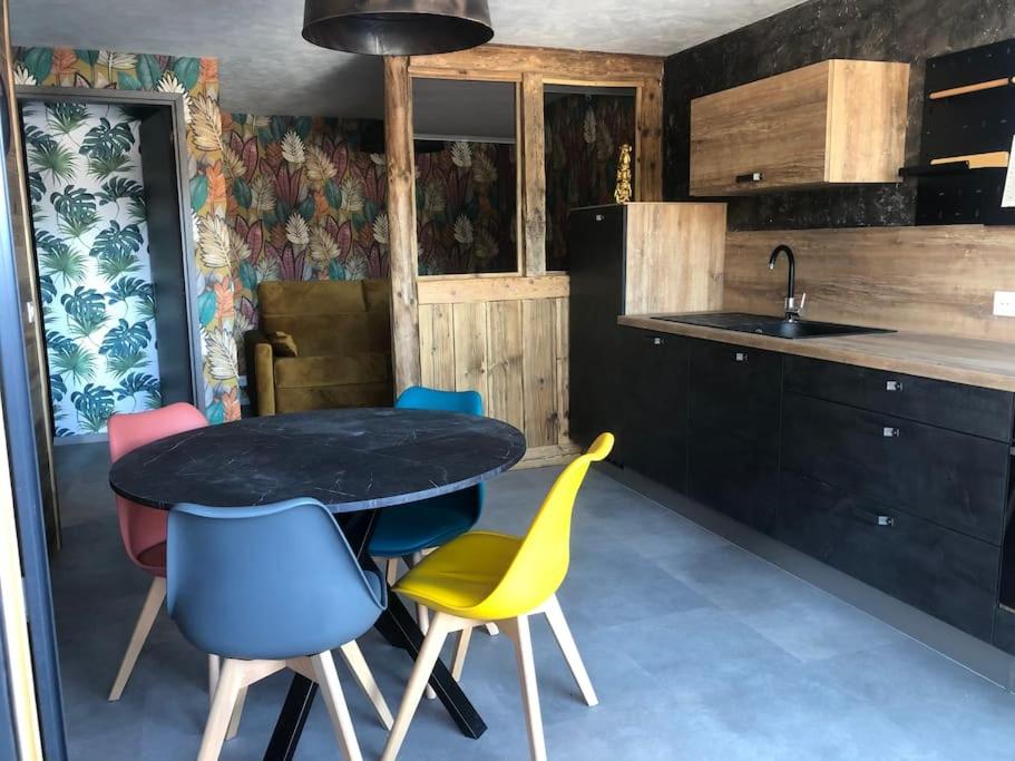a kitchen with a black table and colorful chairs at Le cocon du rondeau(gîte cosy) in Labergement-Sainte-Marie
