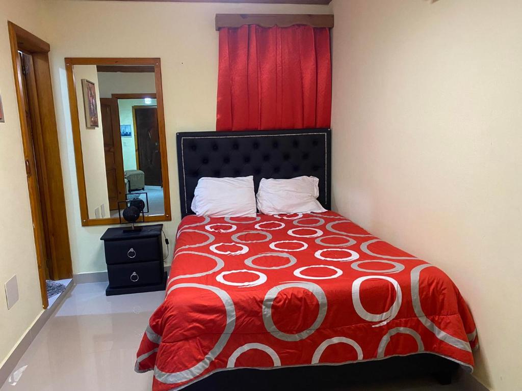 Schlafzimmer mit einem Bett mit einer roten und weißen Decke in der Unterkunft Hotel PedidoSia in Higuey