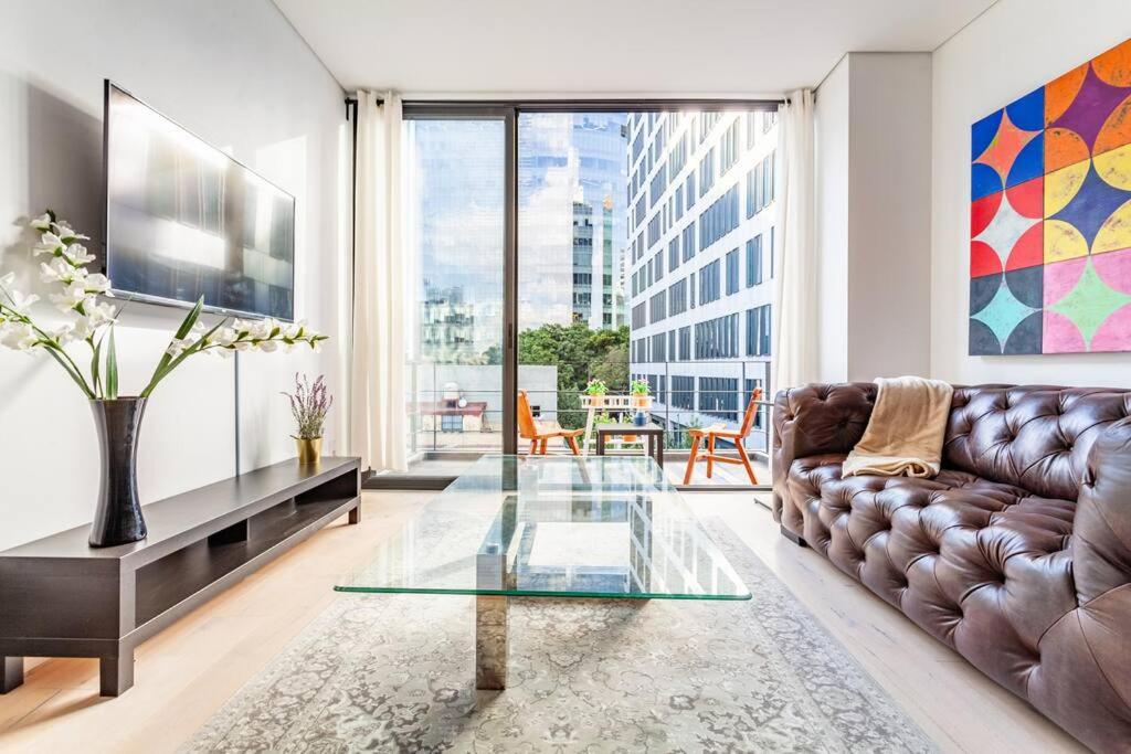 sala de estar con sofá de cuero y mesa de cristal en Penthouse, terraza privada y estacionamiento, en Ciudad de México