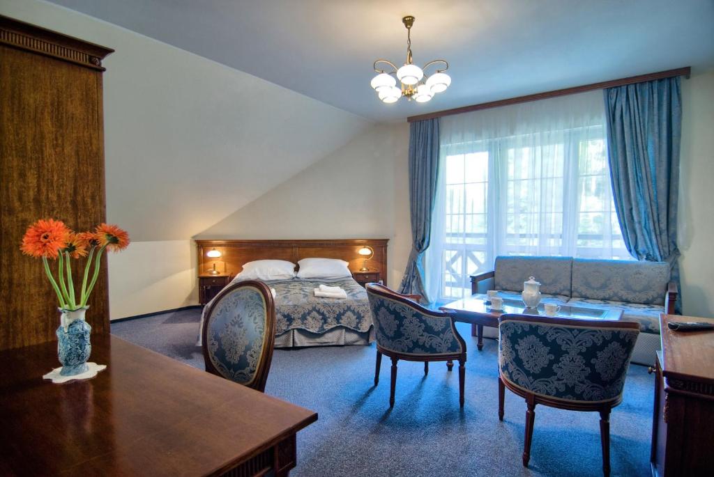シュクラルスカ・ポレンバにあるRezydencja Piastowskaのベッド、テーブル、椅子が備わるホテルルームです。