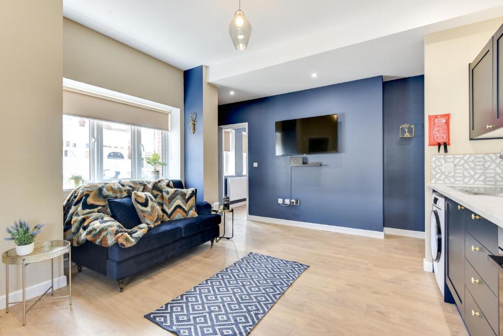uma sala de estar com paredes azuis e um sofá azul em Modern 1 bed close to town and station em Worthing