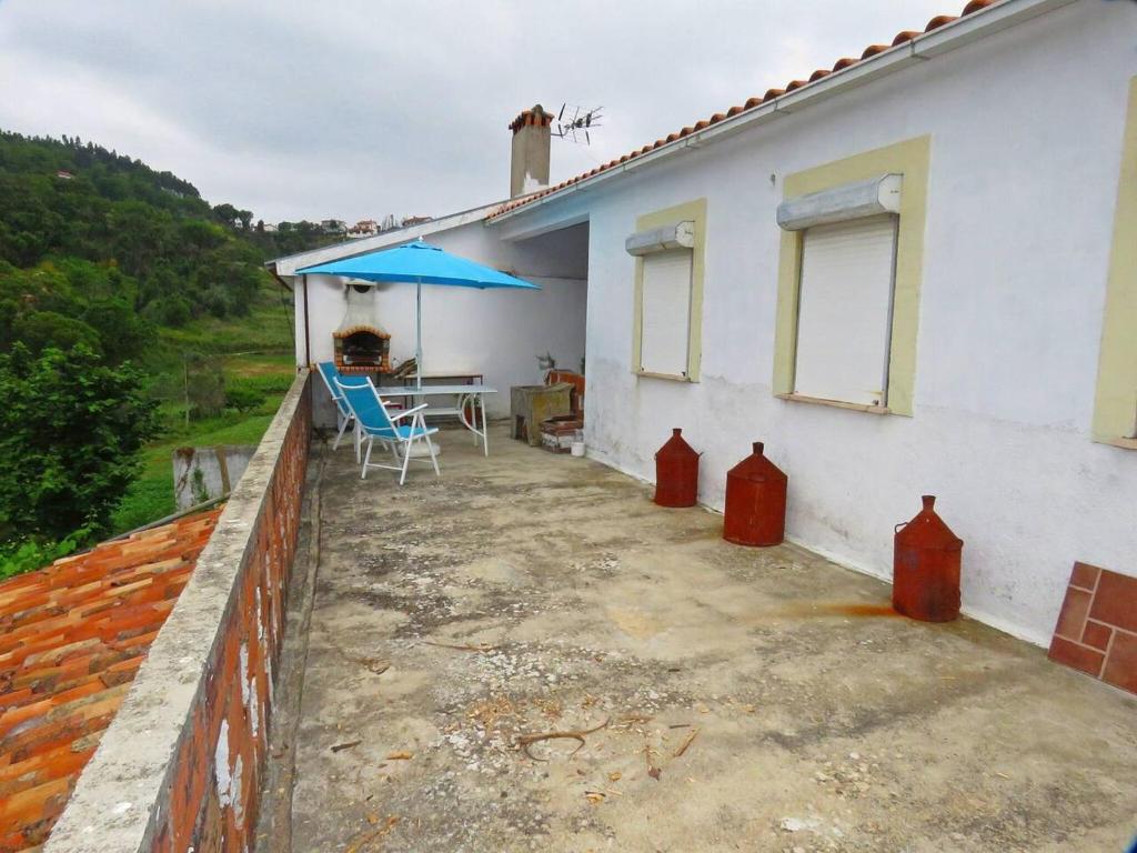 una casa con patio con tavolo e ombrellone di Charming house in Miranda do Corvo + Spacious terrace a Vale de Colmeias