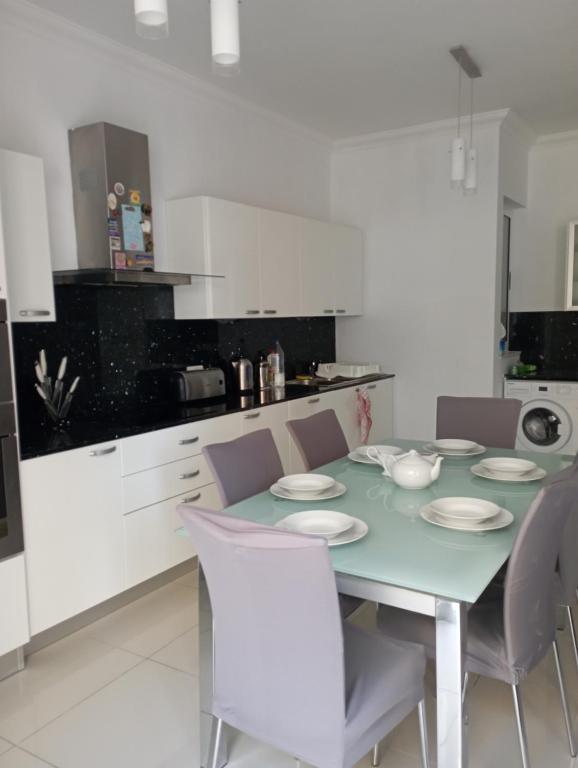 una cucina bianca con tavolo e sedie di Apartment in San Julijans a San Giuliano