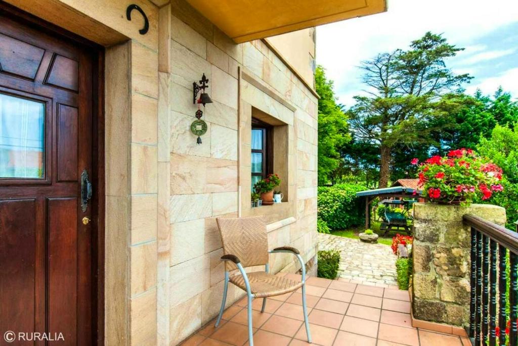 - une terrasse couverte avec une chaise, une porte et des fleurs dans l'établissement 2 bedrooms chalet with terrace and wifi at Orena, à Oreña