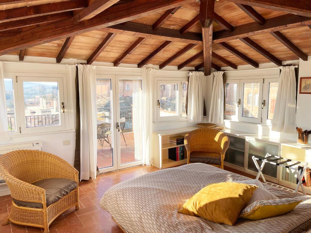 a bedroom with a bed and a desk and windows at Casa della Chiocciola: In Centro in Siena