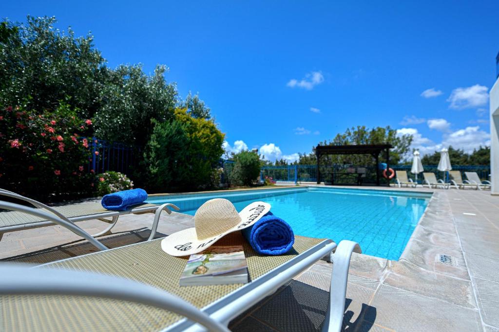 a pair of hats and flip flops sitting on a table by a pool at Azzurro Holiday Villas in Peyia