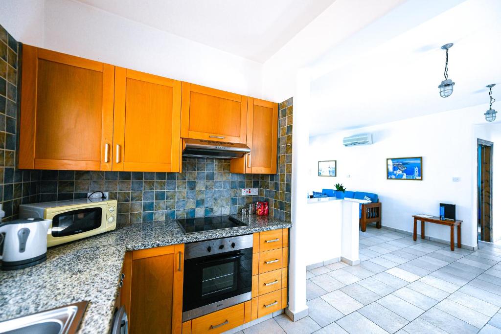 a kitchen with wooden cabinets and a microwave at Azzurro Holiday Villas in Peyia