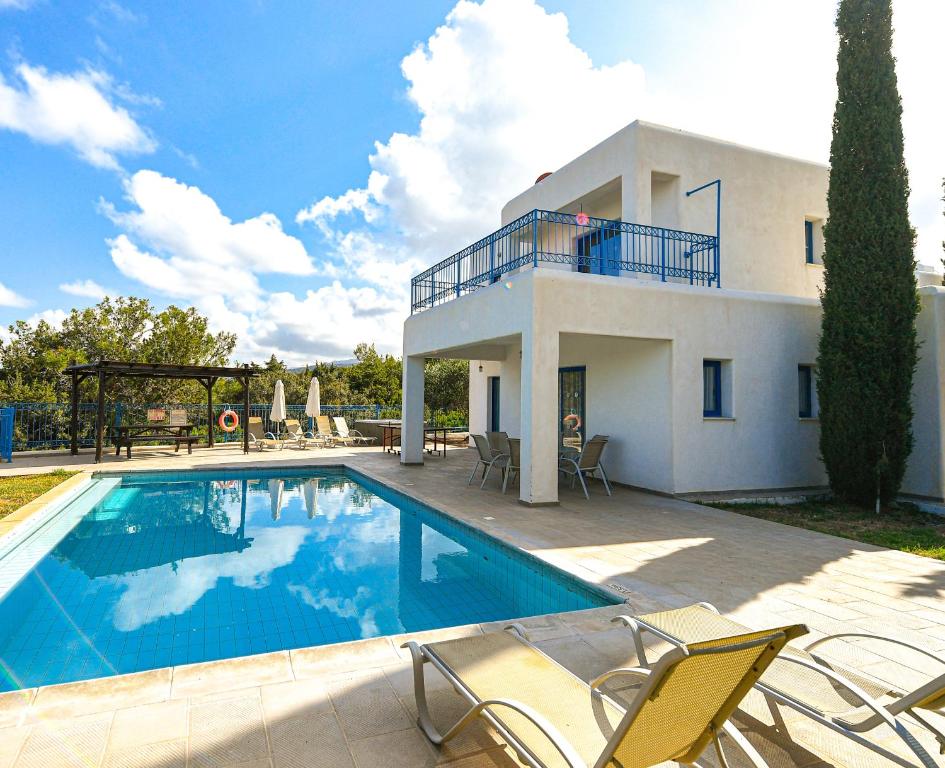 a villa with a swimming pool in front of a house at Azzurro Holiday Villas in Peyia
