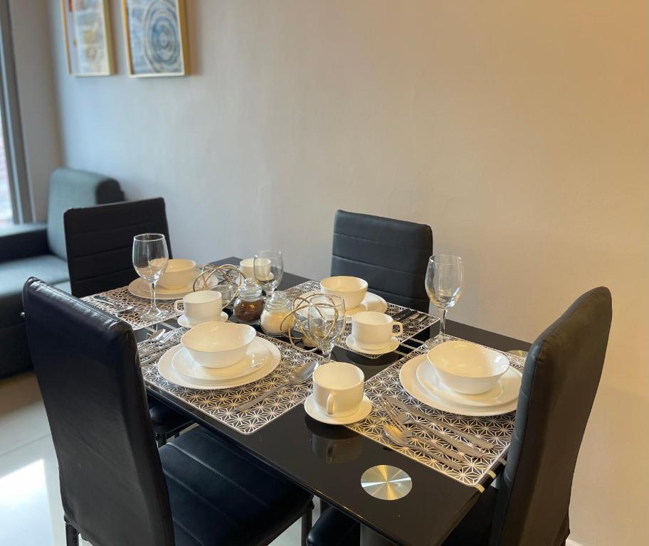 a dining room table with glasses and plates on it at One-bedroom Condo with Balcony in Manila near US Embassy in Manila