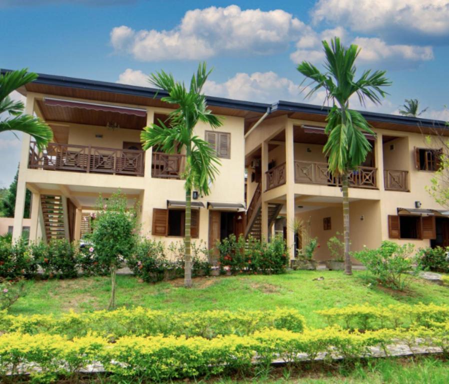 a building with palm trees in front of it at BUNGALOW'S PLAZA KRIBI in Kribi