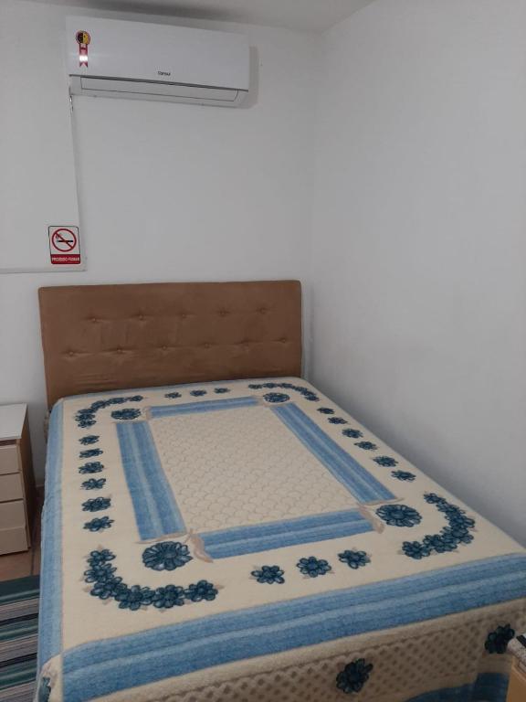 a bed with a blue and white blanket on it at Pousada Goulart in Blumenau