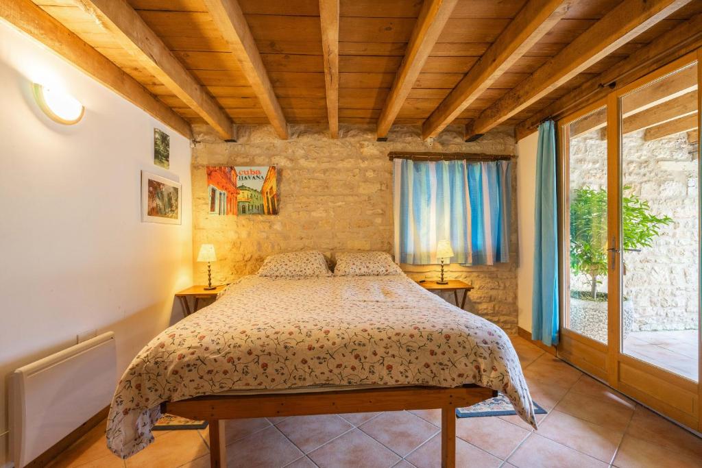 une chambre avec un lit et une grande fenêtre dans l'établissement L'arbre - Gîtes De La Tournerie, à Gémozac