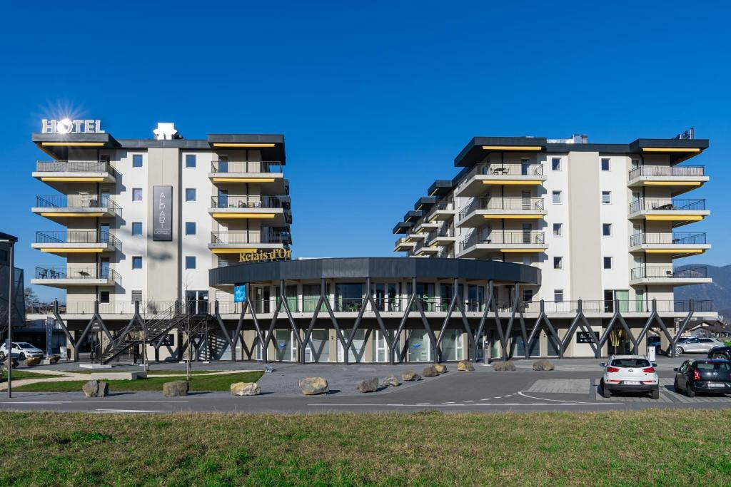 un grande edificio con auto parcheggiate in un parcheggio di Alp Art Hotel a Collombey