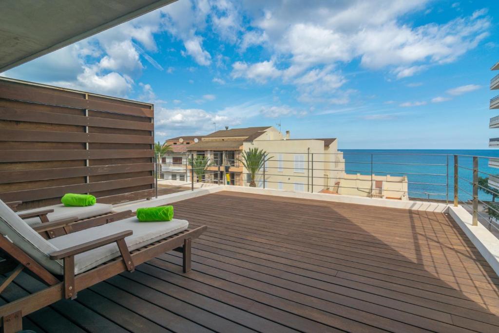 a wooden deck with a bench and the ocean at Luna in Can Picafort