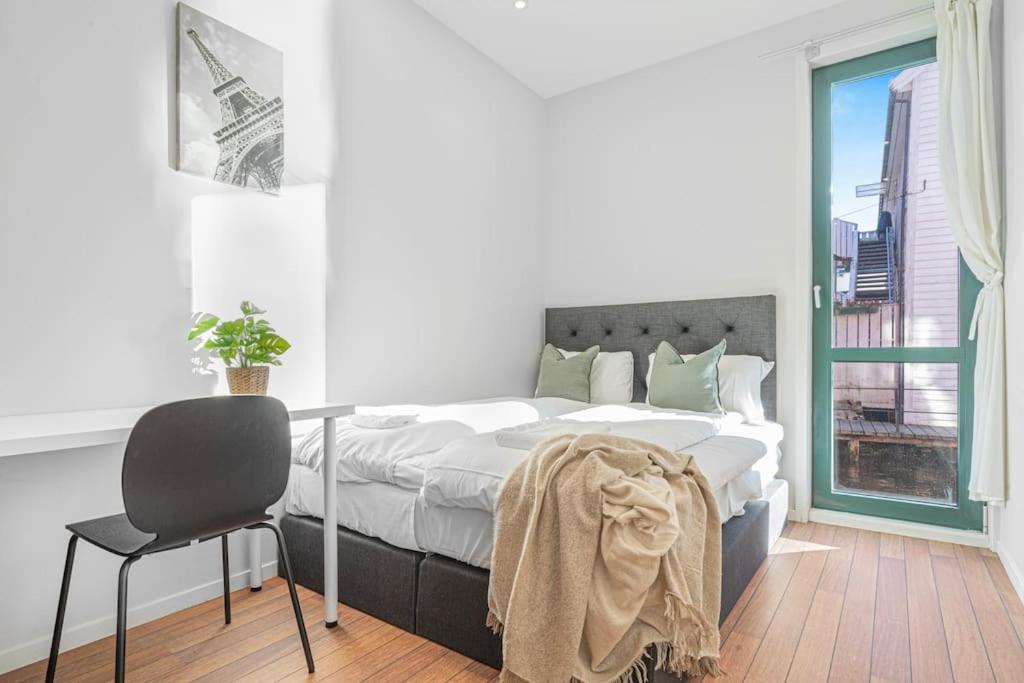 Un dormitorio con una cama y un escritorio y una ventana. en Ocean-view Haven: Take a swim from your window!, en Bergen