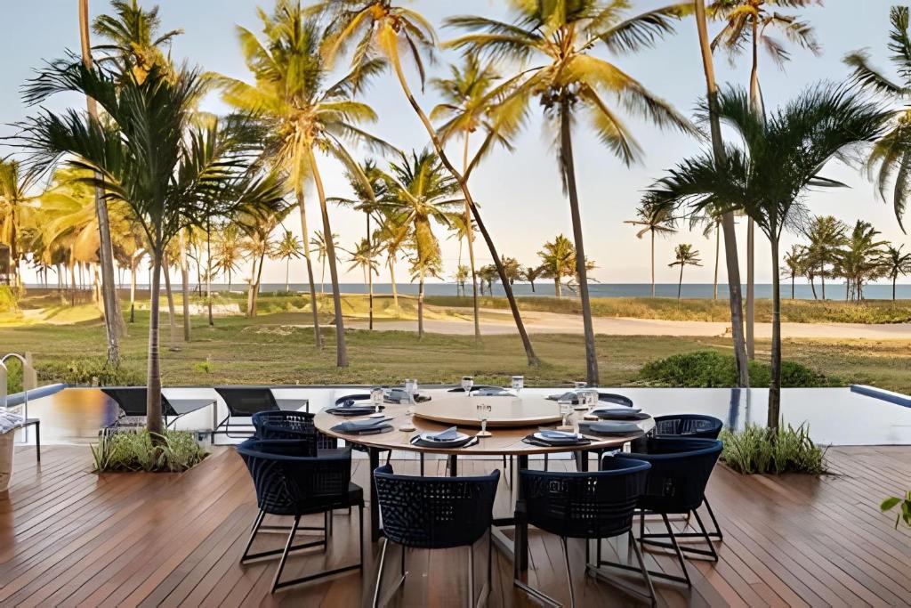 uma mesa e cadeiras num deque com palmeiras em Luxo a 50 m da praia, acesso ao Iberostar Resort na Praia do Forte