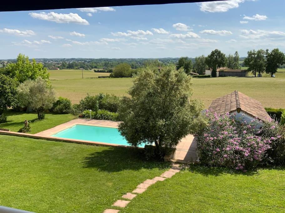 een uitzicht over een zwembad in een veld bij Maison à 6 km de Eymet piscine chauffée. in Roumagne