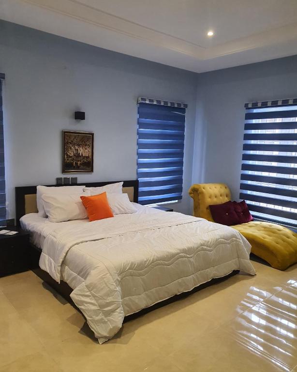 Cet appartement comprend une chambre dotée d'un grand lit, de murs bleus et de fenêtres. dans l'établissement Safari Court, à Abuja