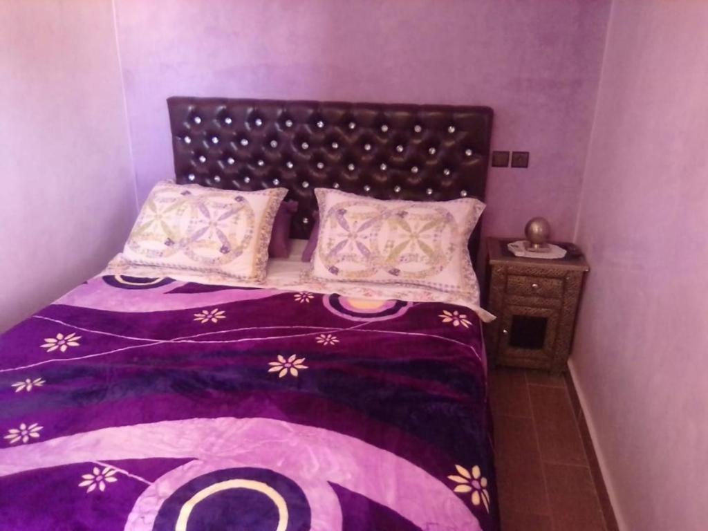 een slaapkamer met een bed met een paars dekbed en kussens bij DAR HIBa in Marrakesh