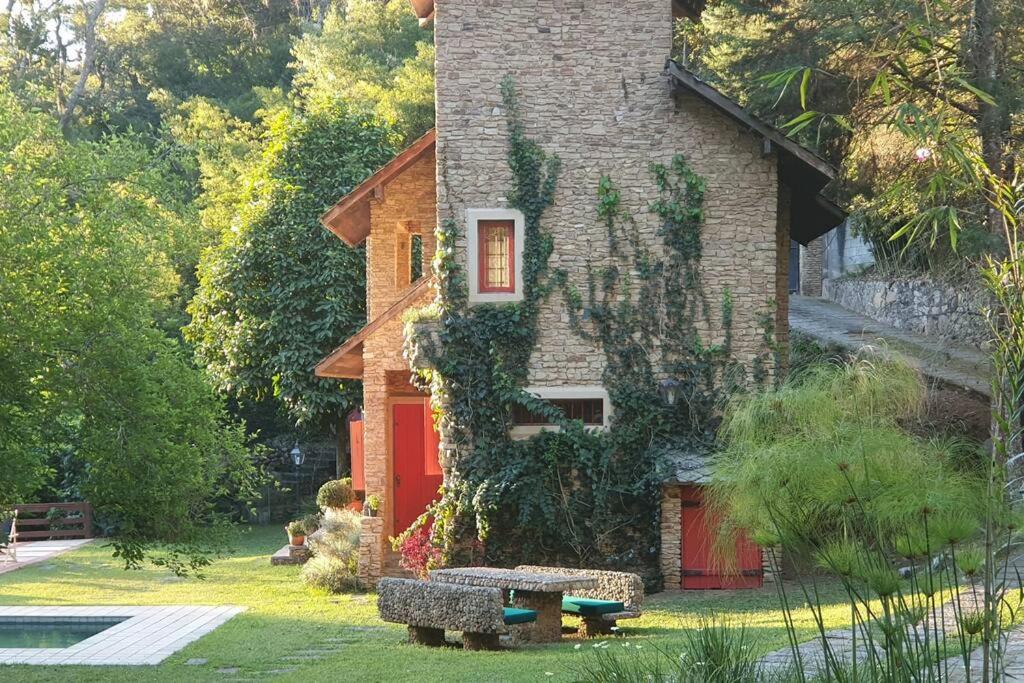 una casa con una puerta roja y un banco en el patio en Chalé de Correas, en Petrópolis