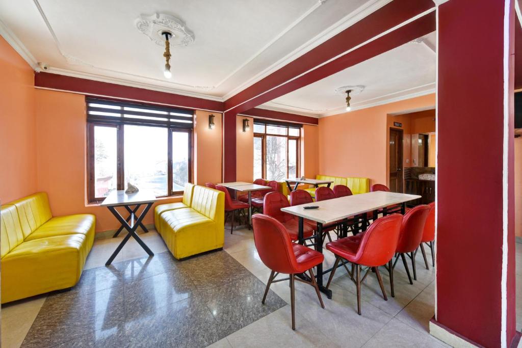 un ristorante con pareti arancioni, tavoli e sedie di Woods Imperial Kufri a Shimla