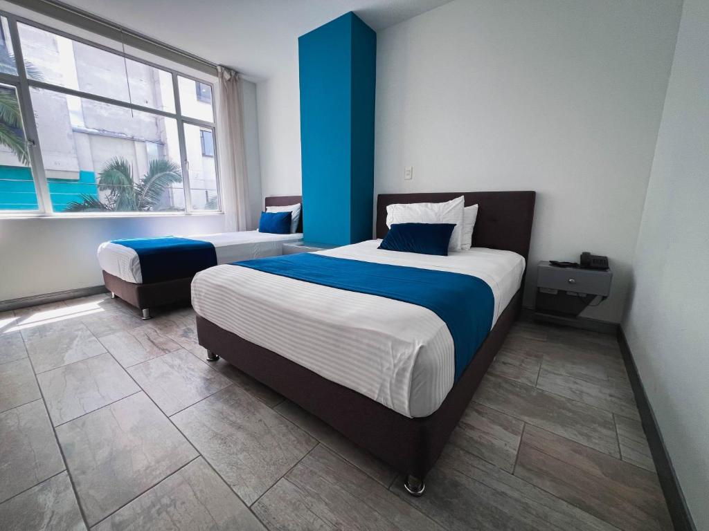 a bedroom with two beds and a large window at Hotel Rosales Gold in Pereira