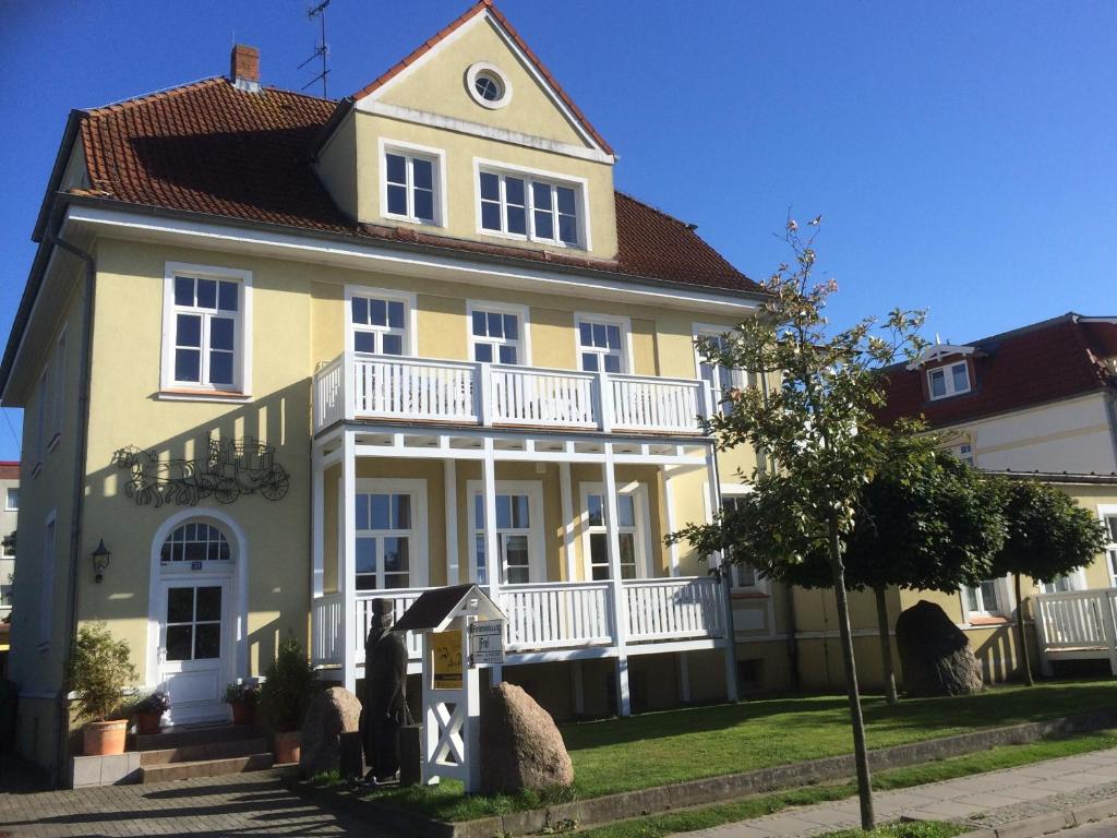 a yellow and white house with a white balcony at Villa Zur Alten Post in Kühlungsborn