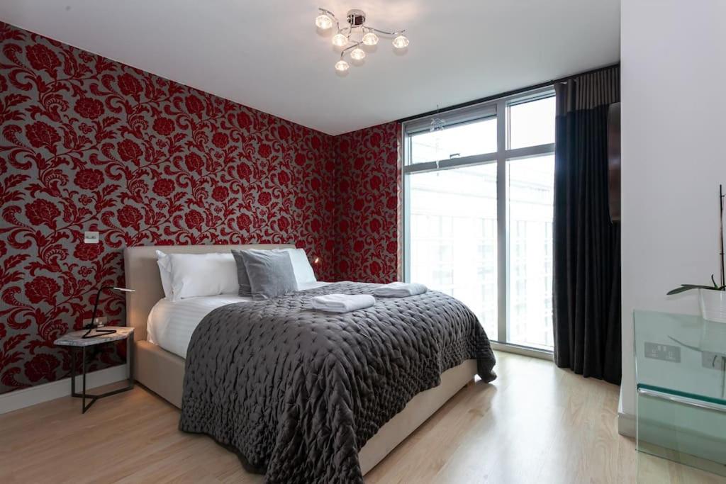 1 dormitorio con cama y pared roja en Iconic Luxury Manchester Apartment, en Mánchester