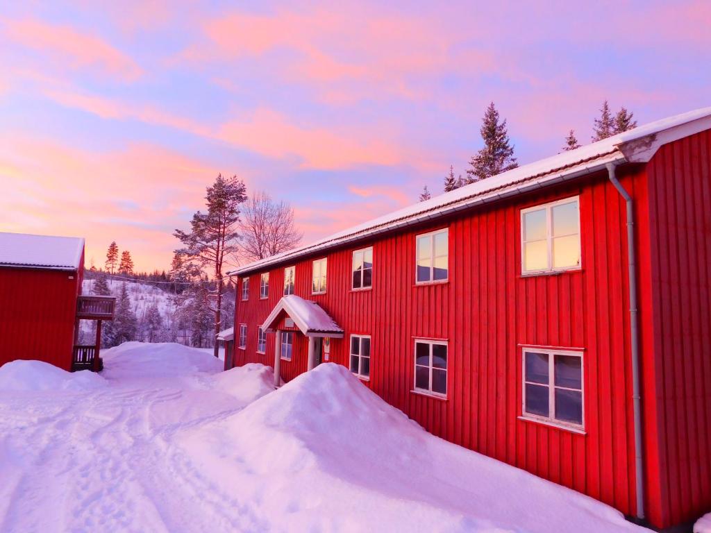 un edificio rojo con nieve delante en Skogsro Forest Hostel en Steinsholt