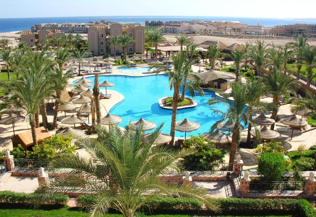 an overhead view of a resort pool with palm trees and umbrellas at Pyramisa Sunset Pearl Apartments in Hurghada