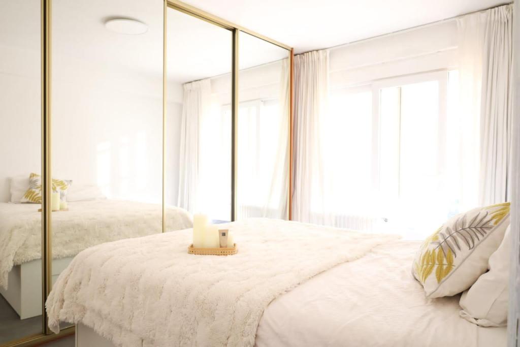 a white bedroom with a mirror and a candle on a bed at Furnished - Bright, Modern apartment in Brussels, 15 minutes walk from the Atomium in Brussels