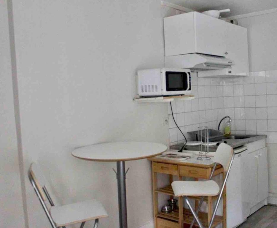 eine kleine Küche mit einem Tisch und einer Mikrowelle in der Unterkunft Suites Rive Gauche - DUPLEX CHARME Fontainebleau in Fontainebleau