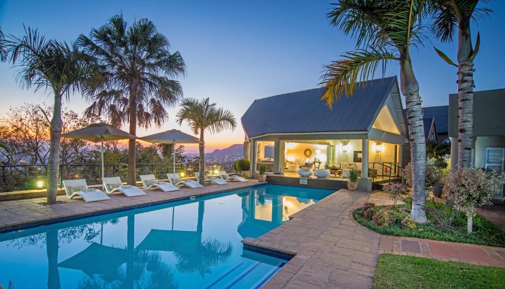 a house with a swimming pool with palm trees at Loerie's Call Guesthouse in Nelspruit