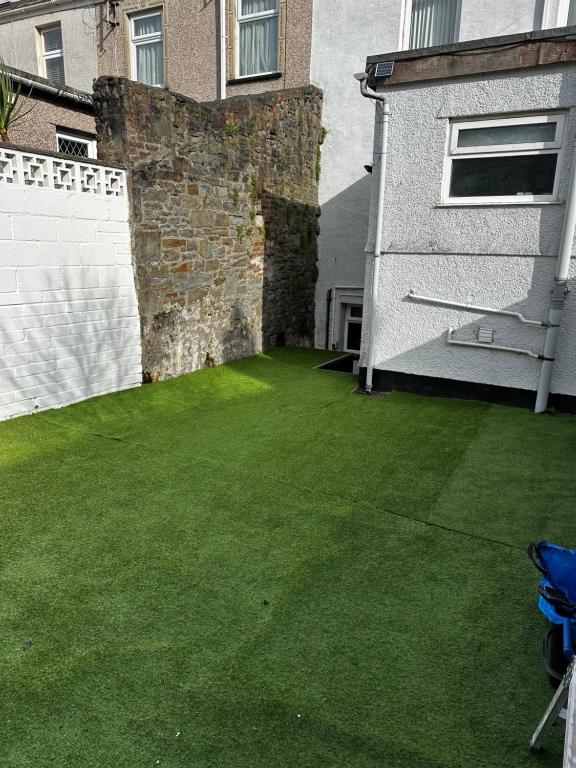 a yard with green grass next to a building at Studio Flat Twin - Town Centre in Merthyr Tydfil