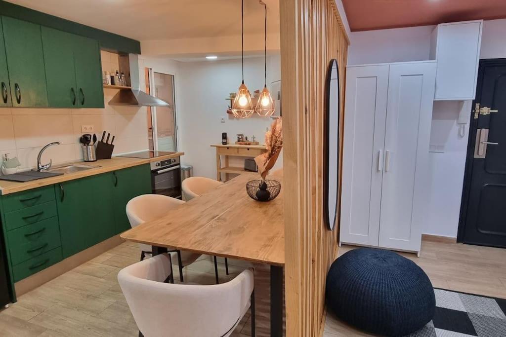 een keuken met groene kasten en een houten tafel en stoelen bij Apartamento Entero Juzgados Alicante in Alicante