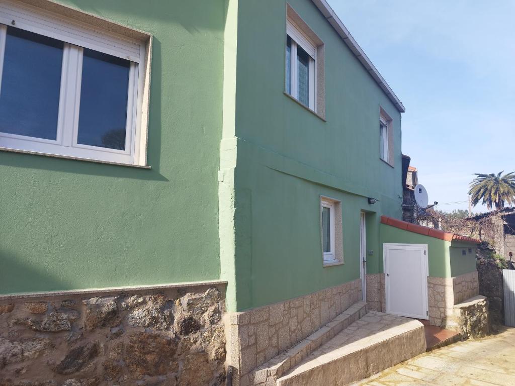 a green building with a white door and windows at Casa Carballa in Os Muinos