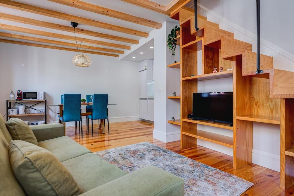 ein Wohnzimmer mit einem Sofa, einem TV und einem Tisch in der Unterkunft Cais das Pedras Duplex by Cozy Stay in Porto