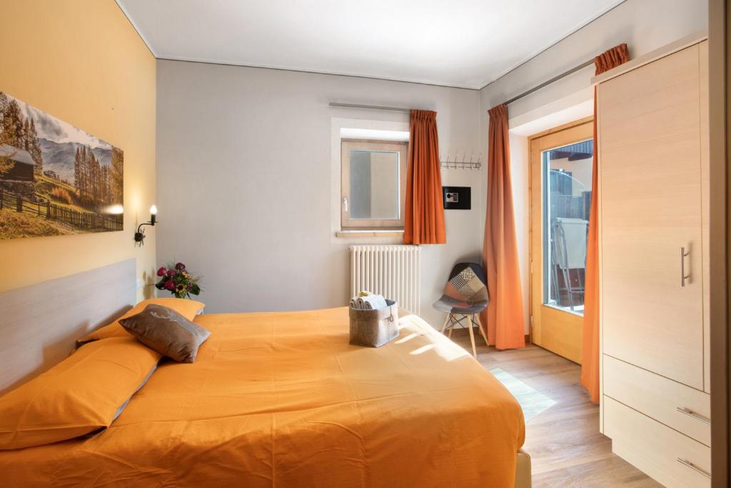 um quarto com uma cama grande e uma colcha laranja em Mountain Apartments Livigno em Livigno