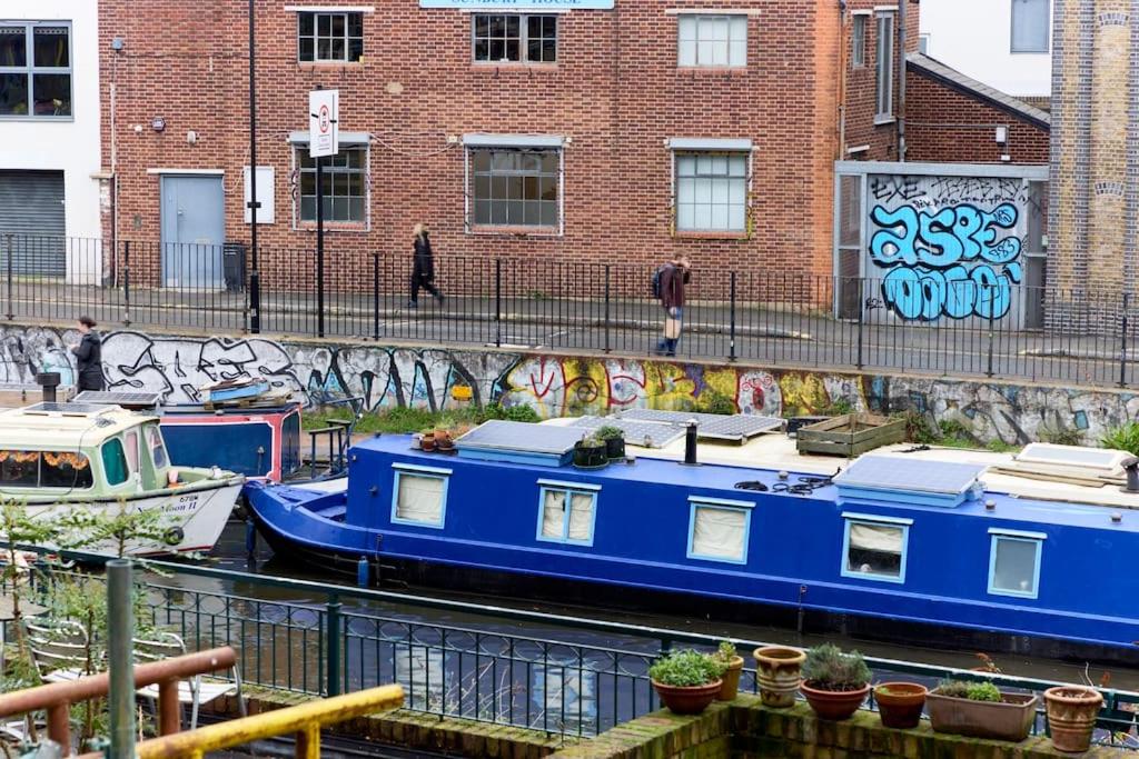 un barco azul está atracado junto a una pared con graffiti en Broadway Market Canal-View Oasis en Londres