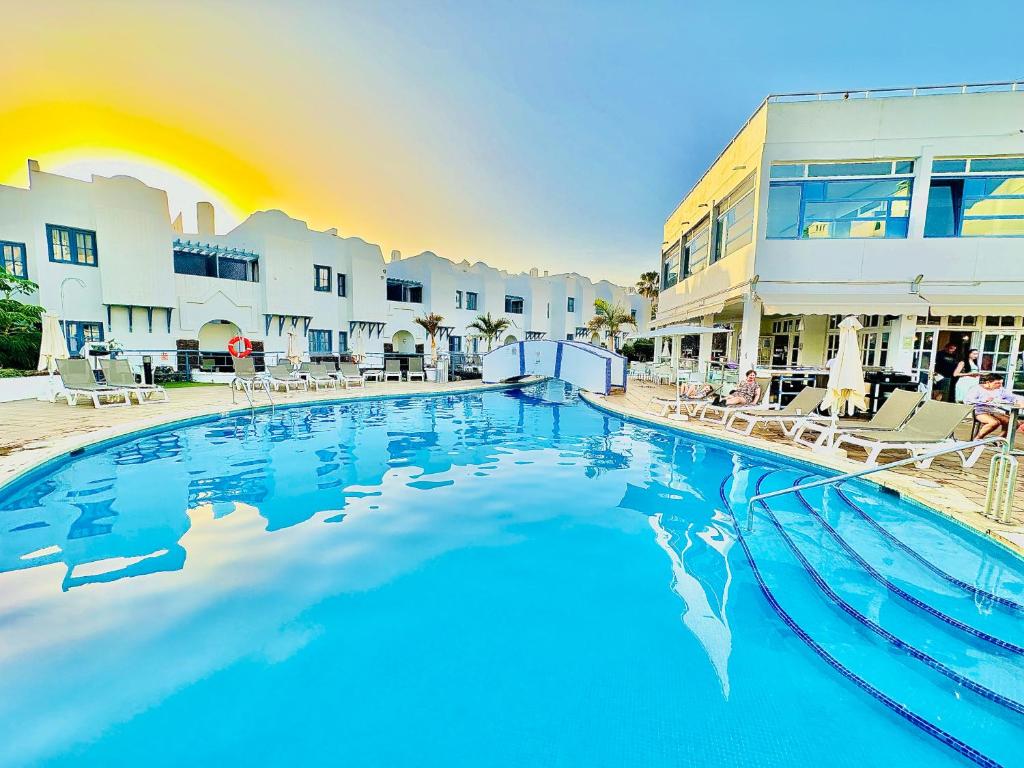 une grande piscine avec des chaises et un bâtiment dans l'établissement Luxury villa Fanabe with private garden, à Adeje