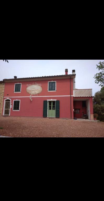 a red house with a green door in front of it at podere il poggetto in Lorenzana