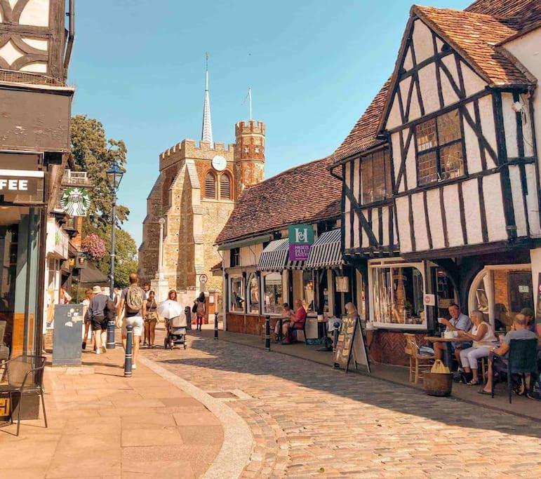 a group of people walking down a street with buildings at Stylish 3 Bed House Hitchin in Hitchin