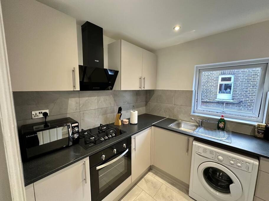 a kitchen with a stove top oven next to a washing machine at 3 bed Hackney/Harringay Flat in London