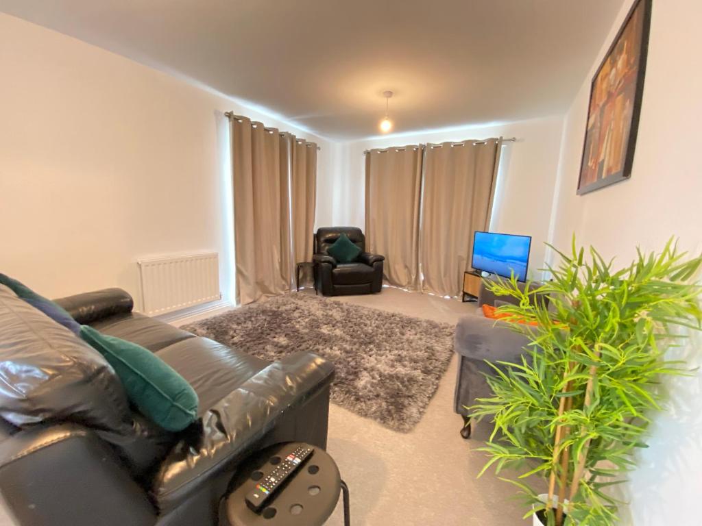 a living room with a leather couch and a chair at Luxurious and Spacious 2 Bedroom Flat in Milton Keynes