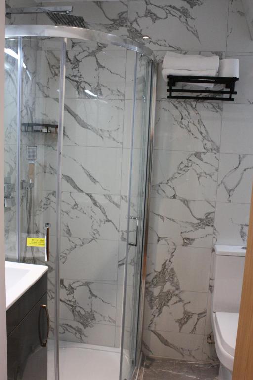 a shower with a glass door in a bathroom at Hotel Olympia in London