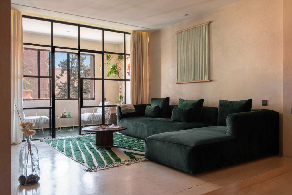 a living room with a green couch and a large window at Appartements Brummell Marrakech in Marrakech