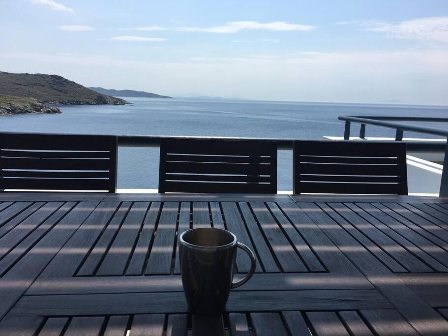 una taza de café sobre una mesa de madera con vistas al agua en Villa Paloma, Tinos Island, en Kardhianí