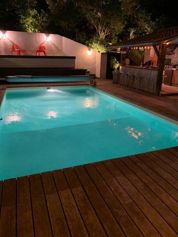 - une piscine bleue avec une terrasse en bois la nuit dans l'établissement Sand Pedro, à Pyla-sur-Mer