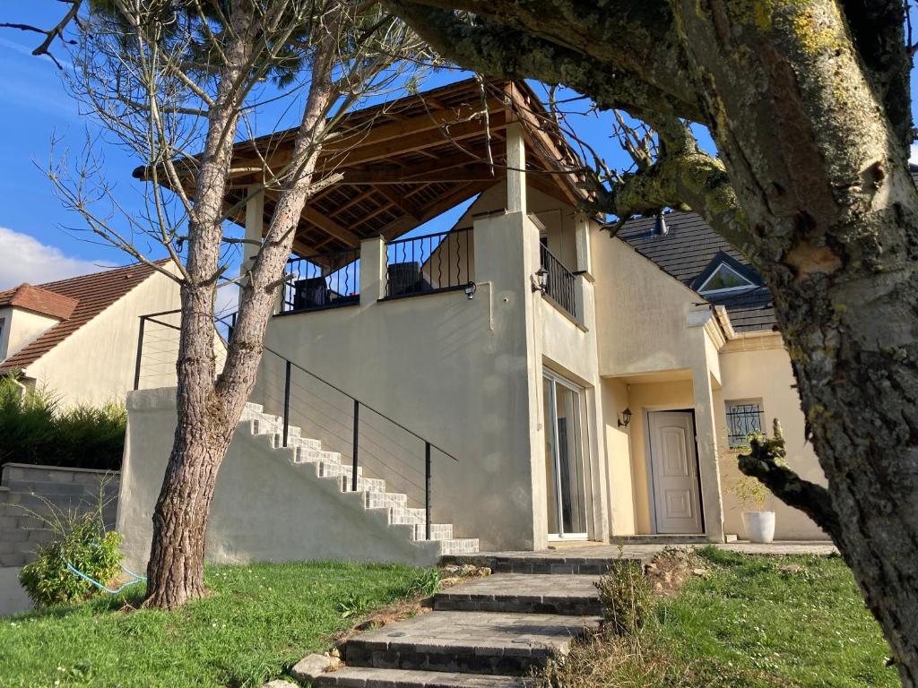 ein weißes Haus mit einer Treppe und einer Veranda in der Unterkunft Chambre triple spacieuse pour 3 Adultes avec terrasse privée - Proche Disneyland Paris in Mareuil-lès-Meaux