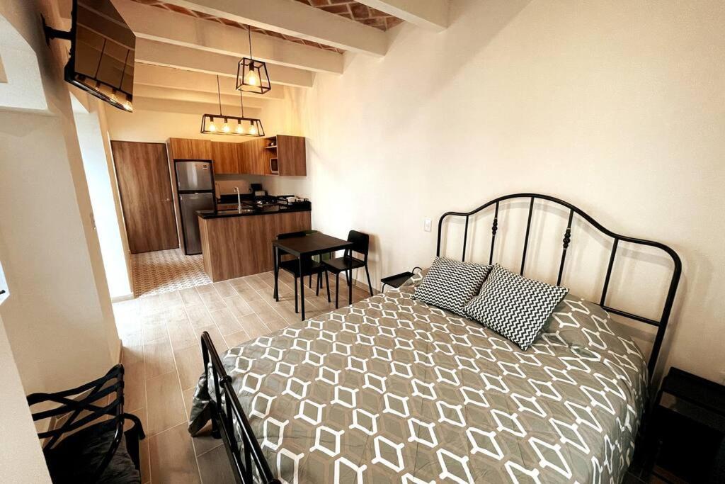 een slaapkamer met een bed en een keuken bij Limones B Encantador Loft en el corazón de Tequis 2p in Tequisquiapan